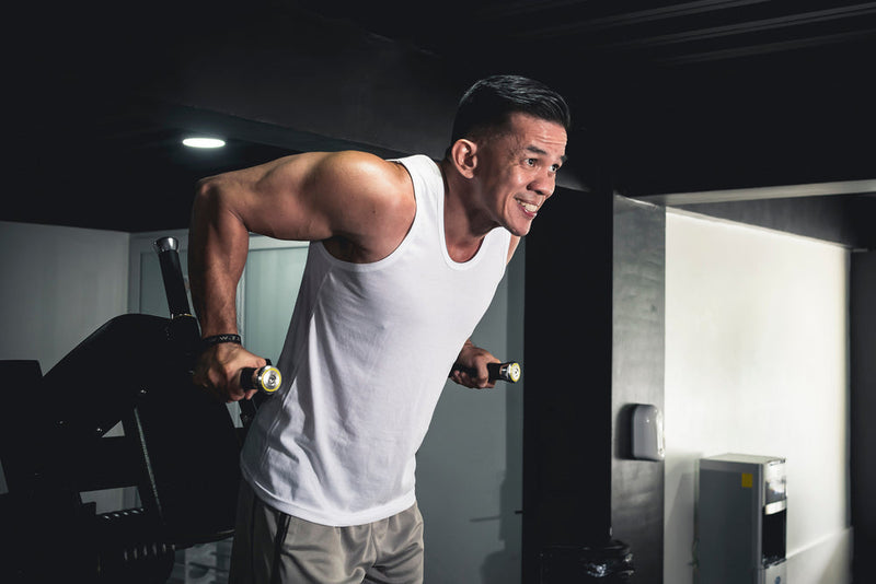 Person trainiert an Dipstation im Fitnessstudio